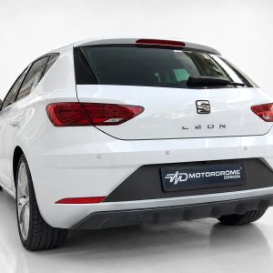 White SEAT Leon hatchback shown from the rear in a bright studio, with red taillights and a Motorodrome Design license plate tag.
