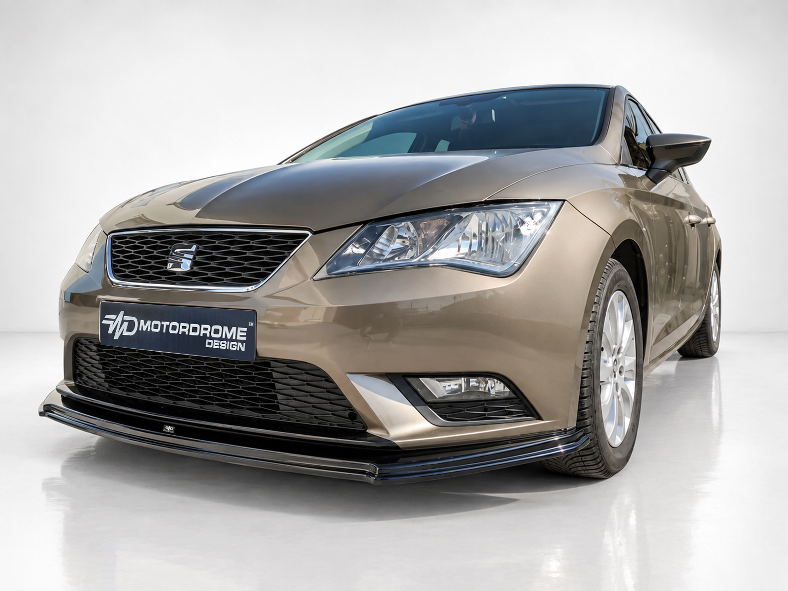 K150-007_1jpg - OPSHOLDERS Front-left view of a metallic beige SEAT car in a studio, with a Mesh grille and logo visible on the bumper plaque reading 'Motordrome Design'