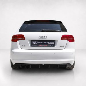 Rear view of a white Audi A3 hatchback showing the tail lights, rear windshield wiper, and a black license plate that reads 'MOTORDROME DESIGN' with logo.
