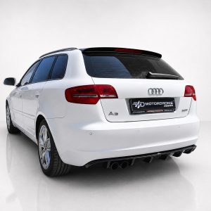Rear view of a white Audi A3 Avant in a studio setting, showing red taillights and quad exhausts on the dark diffuser optioned bumper