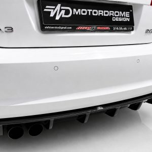 Rear view of a white car showing the A3 badge on the left, a black license plate area with 'MOTORDROME DESIGN', multiple exhaust tips visible at the lower left, and circular parking sensors on the bumper.