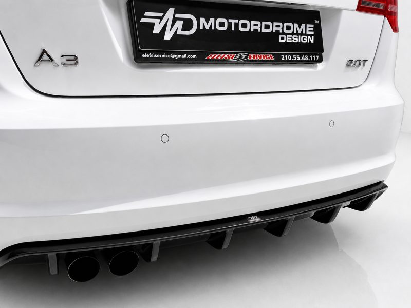 Rear view of a white car showing the A3 badge on the left, a black license plate area with 'MOTORDROME DESIGN', multiple exhaust tips visible at the lower left, and circular parking sensors on the bumper.