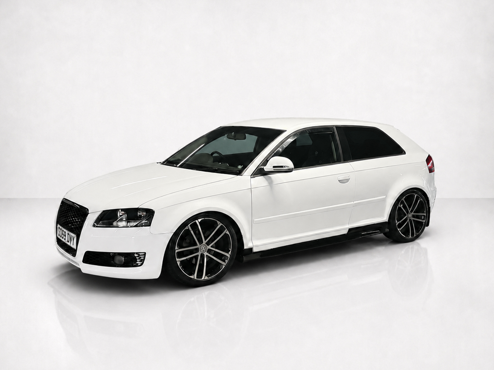 K151-003_1jpg - OPSHOLDERS Three-quarter front view of a white hatchback car with dark windows and black alloy wheels in a studio setting
