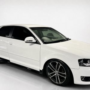 K151-003_2jpg - OPSHOLDERS White sports sedan with large black alloy wheels parked on a glossy white surface, in a studio setting.