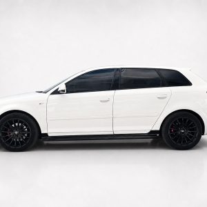 Side profile of a white station wagon with black alloy wheels and dark-tinted windows against a neutral backdrop, showroom style.