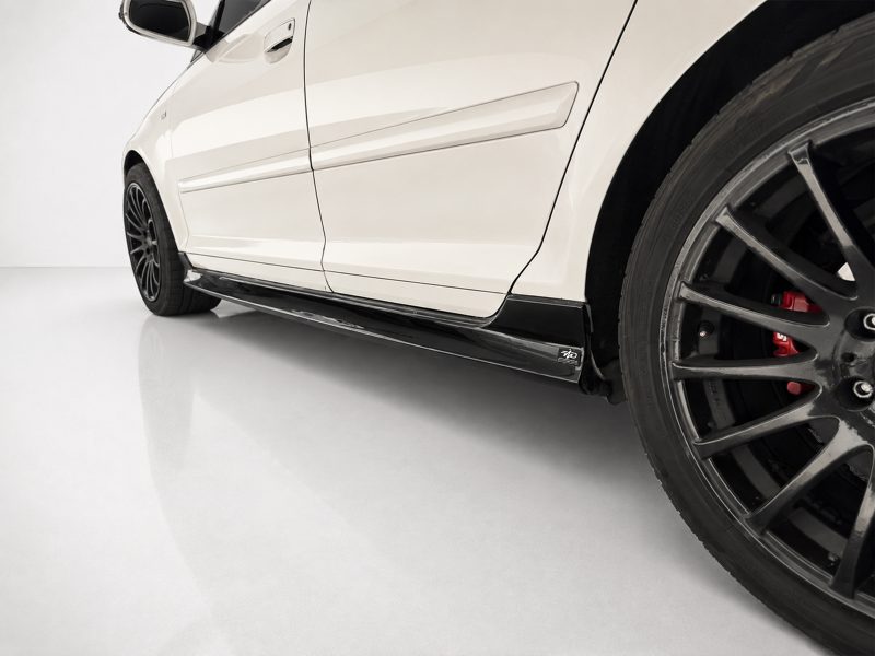 K151-004_3jpg - OPSHOLDERS Close-up of a white car's lower side panel and large black alloy wheel with red brake caliper visible behind it.