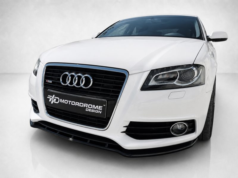 Front view of a white Audi sedan with a black grille, chrome trim, and prominent four-ring emblem on the grille.