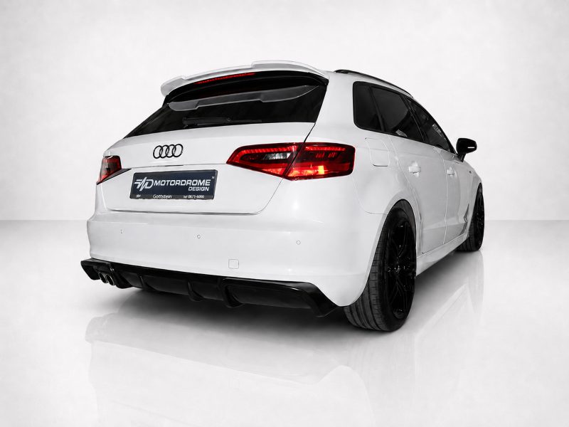 Rear three-quarter view of a white Audi station wagon with a sport rear diffuser and dark alloy wheels in a studio setting.
