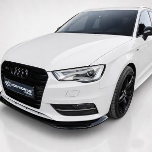 Front three-quarter view of a white Audi sedan with black wheels in a studio, showing a Motordrome Design plate on the front grille.