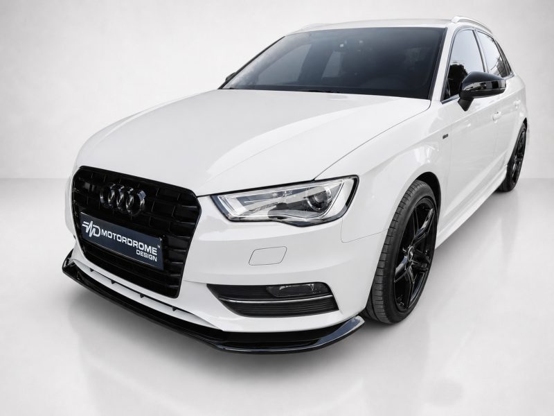 Front three-quarter view of a white Audi sedan with black wheels in a studio, showing a Motordrome Design plate on the front grille.
