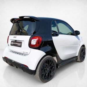 K154-003_4jpg - OPSHOLDERS Rear-left three-quarter view of a two-tone Smart car, black roof and white body with prominent red taillight and branding plate on the tailgate.