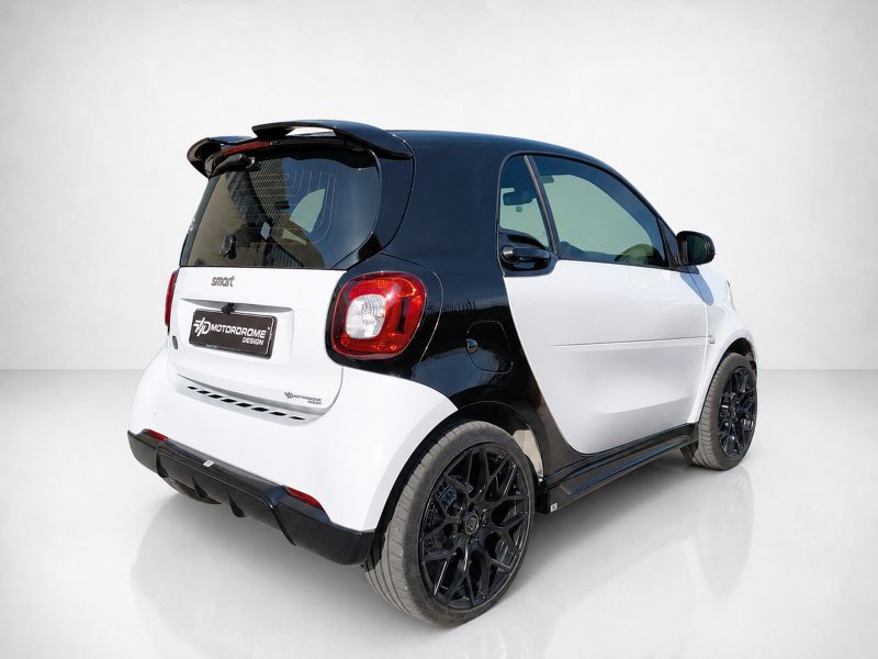 K154-003_4jpg - OPSHOLDERS Rear-left three-quarter view of a two-tone Smart car, black roof and white body with prominent red taillight and branding plate on the tailgate.