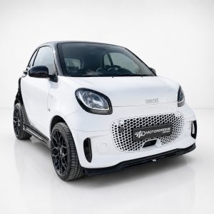 K154-004_2jpg - OPSHOLDERS White Smart car with black roof and honeycomb grille, angled front view in studio setting, front-left perspective, high polish.