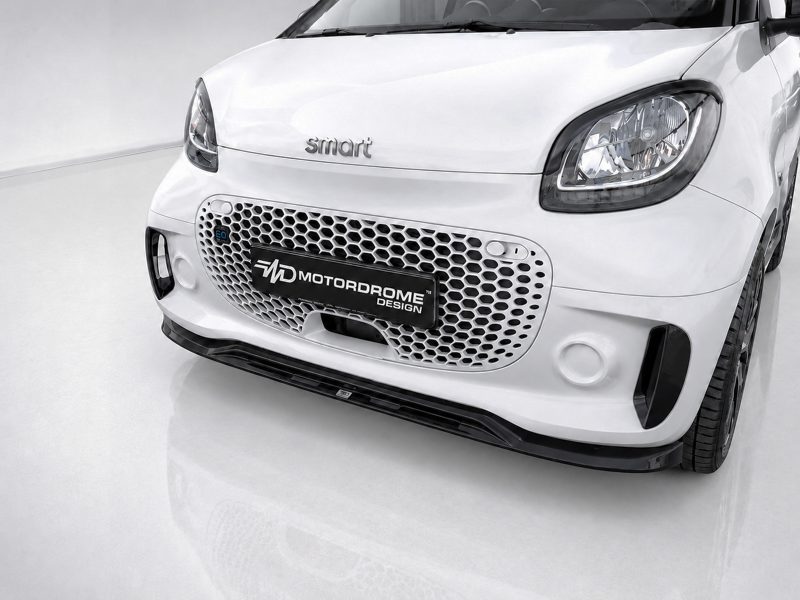 K154-004_4jpg - OPSHOLDERS Front view of a white Smart car with a honeycomb grille and a Motordrome Design plate.