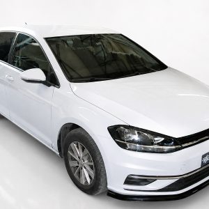 White Volkswagen hatchback photographed in a bright studio, angled from the front-right showing the grille and headlights.