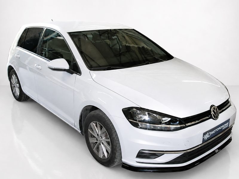 White Volkswagen hatchback photographed in a bright studio, angled from the front-right showing the grille and headlights.