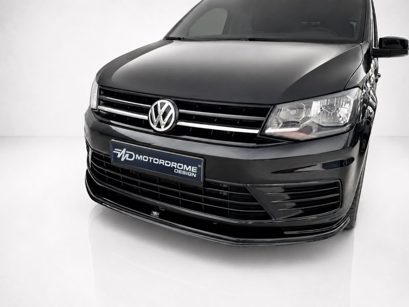 Close-up of the front of a black Volkswagen van with chrome grille and emblem in a studio setting.