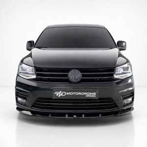 Front view of a glossy black van with VW emblem and illuminated headlights, featuring a MotorDrome Design plate at the bumper.