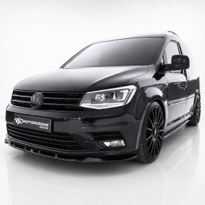 Black customized van with large black multi-spoke wheels, front view in a white studio, Motordrome Design plate visible