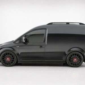Side view of a black cargo van with large black alloy wheels and red center caps.
