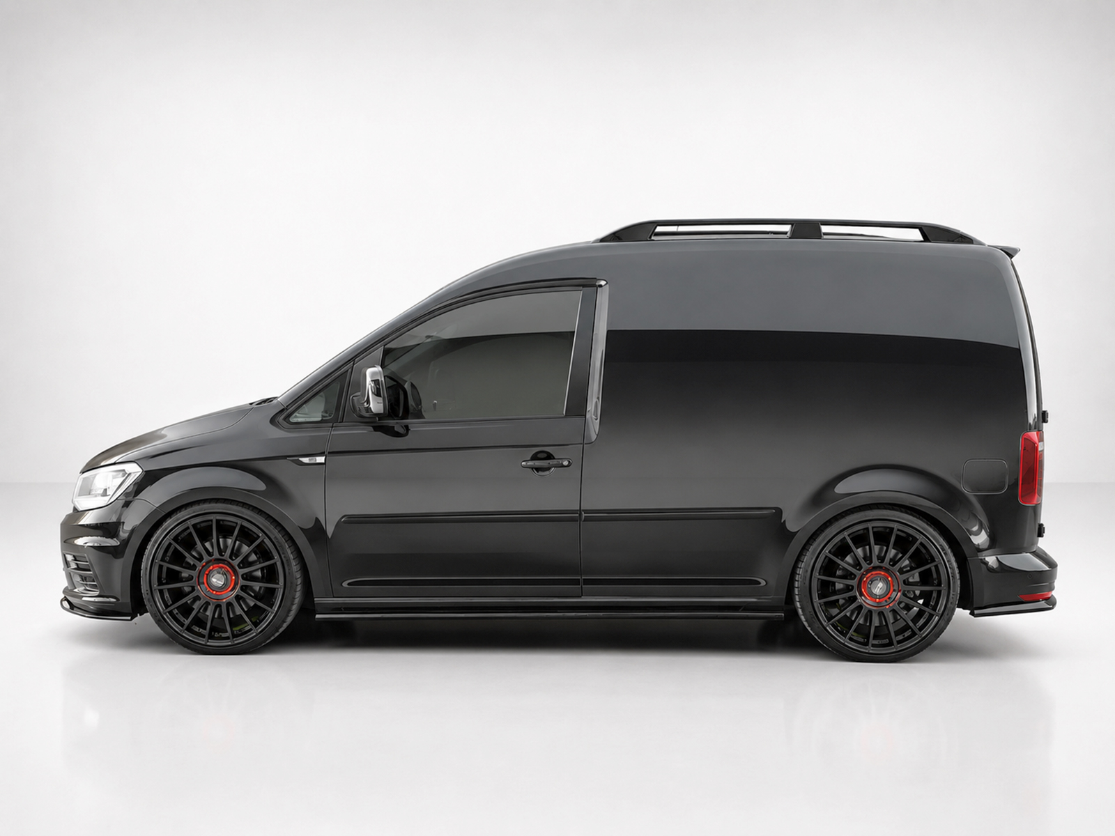 K157-003_1jpg - OPSHOLDERS Side view of a black cargo van with large black alloy wheels and red center caps.