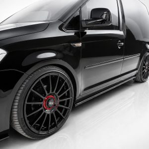 K157-003_2jpg - OPSHOLDERS Close-up of a glossy black van showing the front fender, door, and a large multi-spoke wheel with a red center cap.