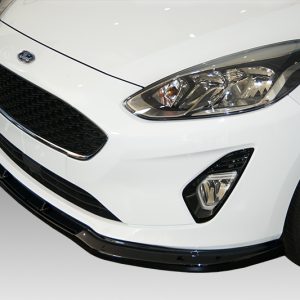 Close-up of the front end of a white Ford car, featuring the black honeycomb grille, headlight, fog light, and part of the wheel.