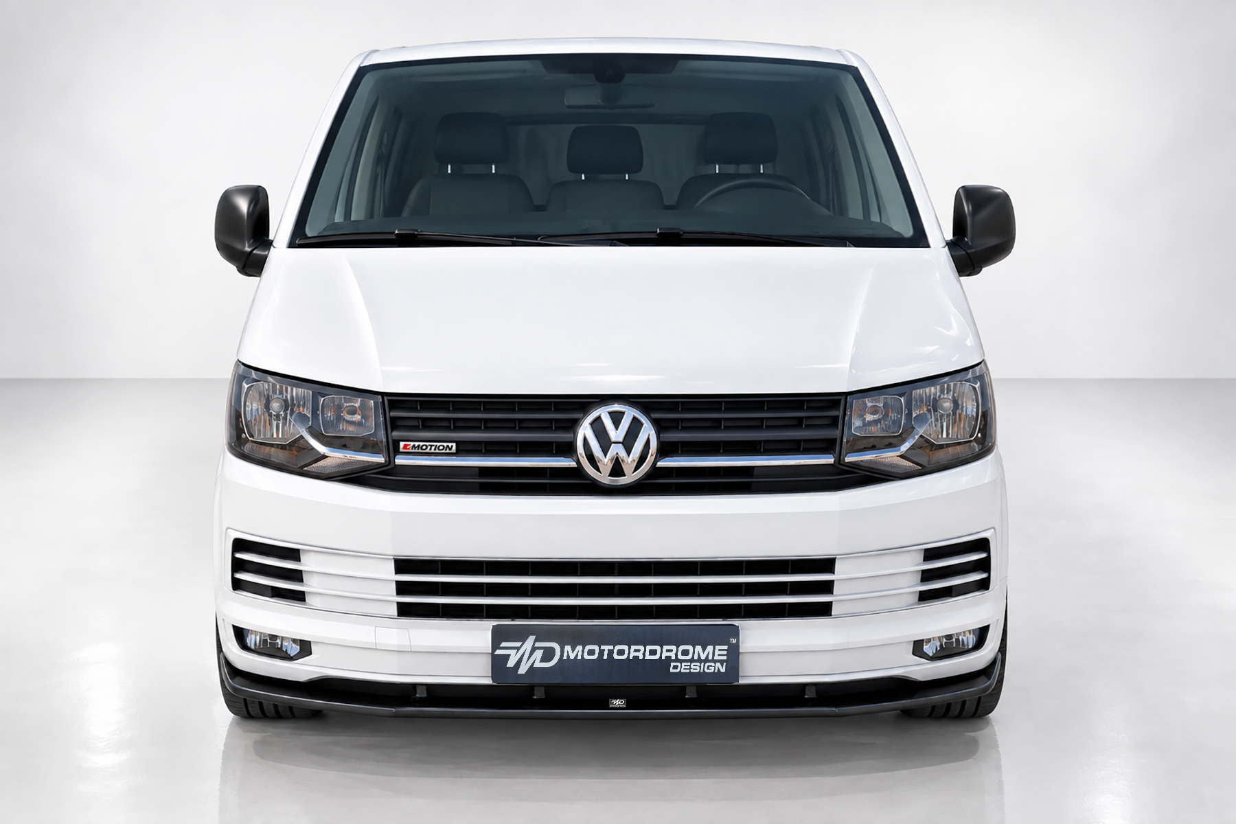 K159-001_2jpg - OPSHOLDERS Front view of a white Volkswagen van in a studio, showing the grille, headlights, and Motordrome Design plate on the bumper.