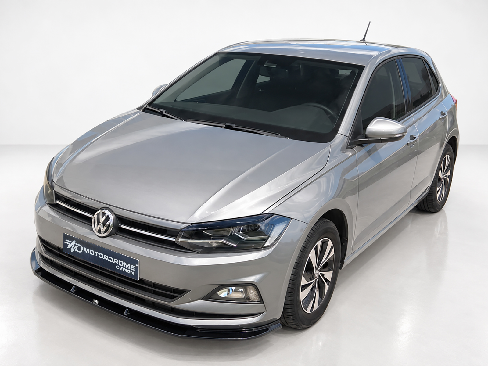 K162-001_2jpg - OPSHOLDERS Front-left angled view of a silver Volkswagen sedan in a bright studio showroom, glossy finish visible.
