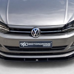 K162-001_4jpg - OPSHOLDERS Front view of a silver Volkswagen car showing the logo, headlights, and a Motordrome Design license plate.