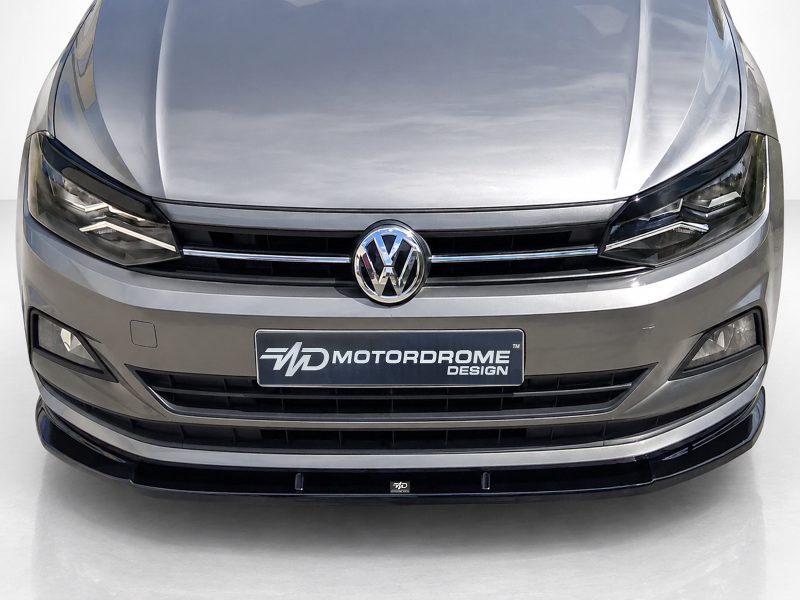 K162-001_4jpg - OPSHOLDERS Front view of a silver Volkswagen car showing the logo, headlights, and a Motordrome Design license plate.