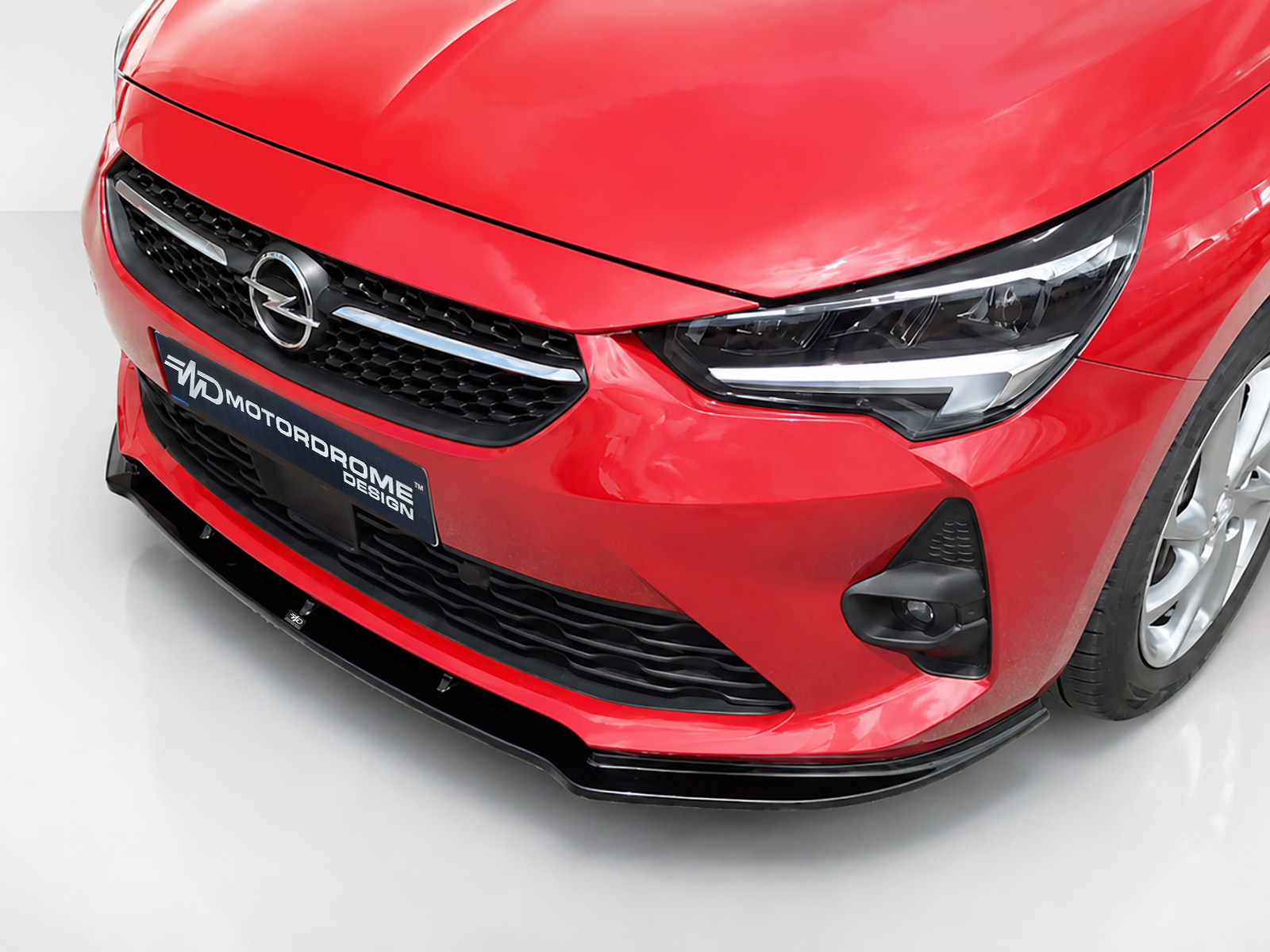 K163-001_2jpg - OPSHOLDERS Close-up of the red Opel car front with emblem, grille, and headlight.