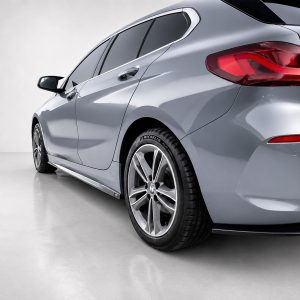 Rear three-quarter view of a silver BMW car in a studio, showcasing its alloy wheels and red taillights.