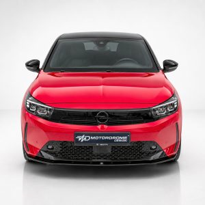 Front-on view of a red car with a black grille, parked in a studio setting with a light gray background.