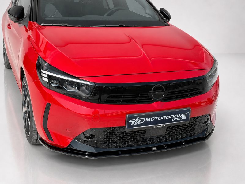 K163-006_3jpg - OPSHOLDERS Red sedan front view with black grille and Opel emblem, showroom floor setting, angled toward the right side of the image