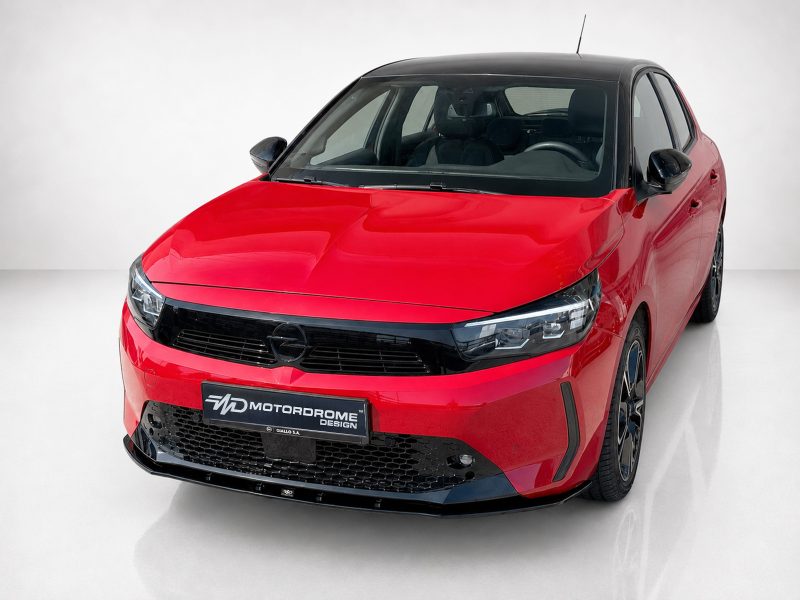 K163-006_4jpg - OPSHOLDERS Front three-quarter view of a red compact hatchback with a black roof and glossy black grille in a studio setting, showing Opel badge.