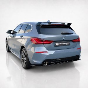 Blue BMW hatchback viewed from rear-left, showcasing aftermarket spoiler and rear diffuser on a glossy white backdrop.