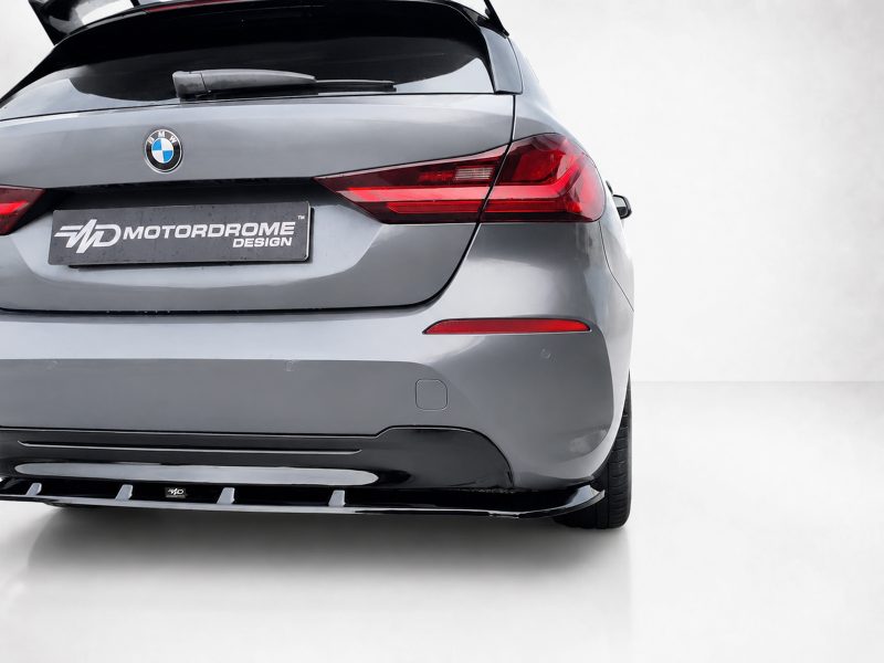 Rear view of a gray BMW hatchback with a Motordrome Design license plate and red taillights