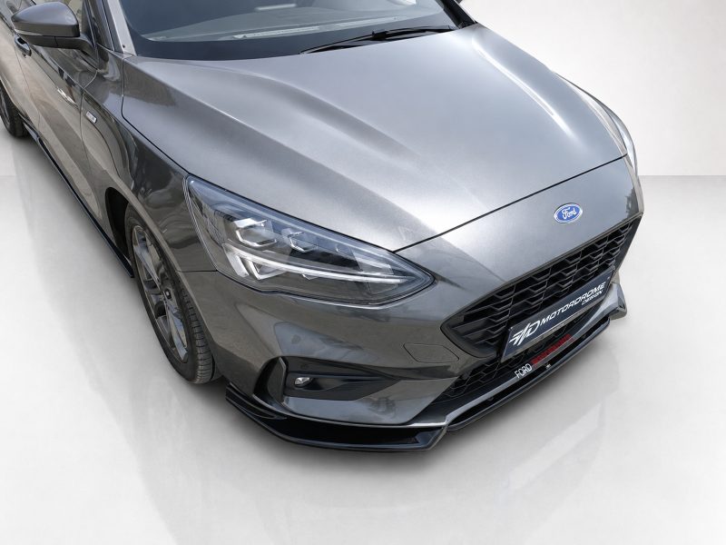 Front-angle view of a gray Ford car showing its hood, headlight, and honeycomb grille.