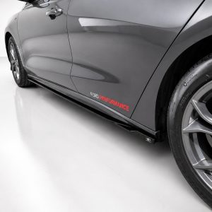 Side view of a gray Ford car with a black side skirt and prominent wheel, displaying the 'FORD PERFORMANCE' branding along the door panel.
