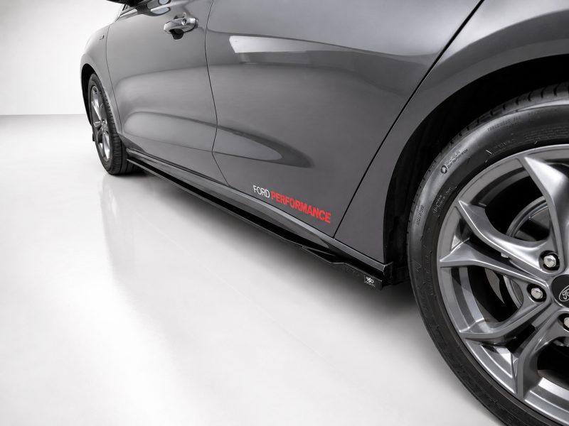 Side view of a gray Ford car with a black side skirt and prominent wheel, displaying the 'FORD PERFORMANCE' branding along the door panel.