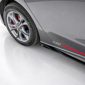 Close-up of a gray Ford car showing alloy wheel, red brake caliper, and the 'FORD PERFORMANCE' branding along the side skirt.