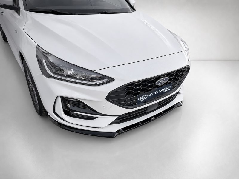 Front end of a white Ford sedan with a black honeycomb grille and prominent headlight details, shown in a studio setting to highlight the car’s design features and front bumper.