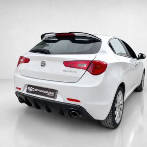 White Alfa Romeo Giulietta hatchback shown from the rear three-quarter, in a bright studio setting with a glossy floor.