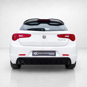Rear view of a white Alfa Romeo Giulietta with red taillights in a studio setting; license plate shows Motordrome Design.