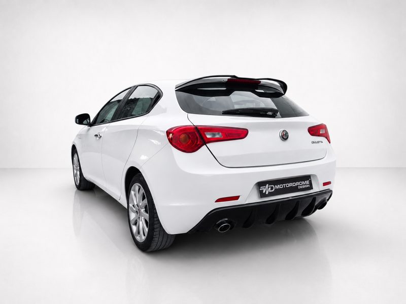 Rear three-quarter view of a white Alfa Romeo Giulietta hatchback in a bright studio setting.