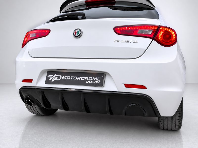Rear view of a white Alfa Romeo Giulietta with red taillights and a black diffuser feature, shows a motorsport design plate.