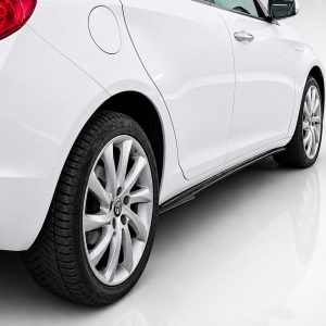 White car seen from the rear-side, showing the back wheel and door panel in a bright studio setting, indoors
