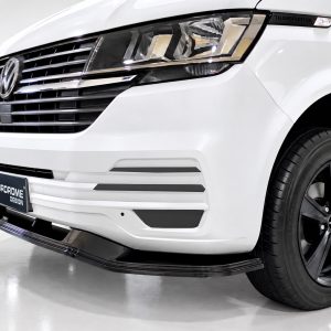 Front-left view of a white Volkswagen Transporter with a bold grille and aftermarket front lip by Motordrome Design, showcasing the van’s distinctive headlight cluster and badge area.