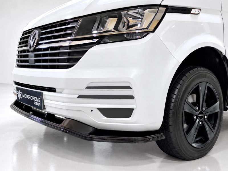 Front-left view of a white Volkswagen Transporter with a bold grille and aftermarket front lip by Motordrome Design, showcasing the van’s distinctive headlight cluster and badge area.